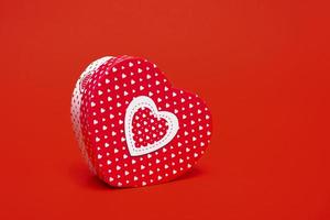 mockup van een doos in de vorm van een hart op een rode achtergrond. close-up met kopie ruimte foto