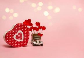 geschenkdoos en retro auto met papieren hartjes op een roze achtergrond. valentijnsdagconcept, verjaardag, moederdag en gelukkige verjaardagsgroet, copyspace, close-up foto