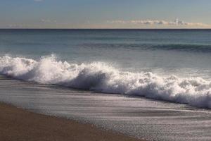 kalme zee strand met spatten golf zeegezicht. foto