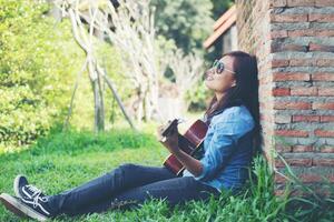 jonge hipster meisje zit een gitaar te spelen en te zingen. foto