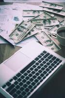 werkplaats van de handelaar. de tafel gedekt door bankbiljetten, toetsenbord en financiële grafieken. zakelijk financieel werken. foto