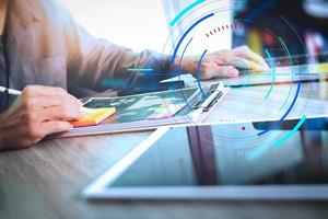 designer hand werken en slimme telefoon en leeg scherm laptop en digitale tablet op houten bureau op kantoor foto