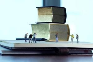 creatief ideeconcept - miniatuurfotograaf met uitstekend gouden boek op open document notitieboekje foto