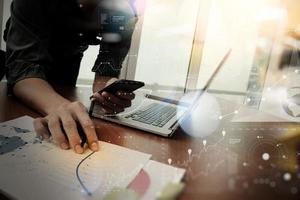 close-up van de hand van de zakenman die werkt op een laptopcomputer met een digitale laag bedrijfsgrafiekinformatiediagram op houten bureau als concept foto
