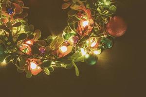 groet seizoen concept.kerst krans met decoratief licht op donkere houten achtergrond foto