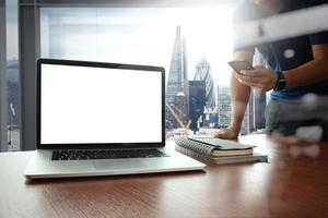 designer hand werken en slimme telefoon en laptop op houten bureau op kantoor foto