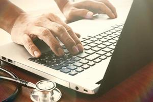 artsenhand die met laptop computer in medisch werkruimtebureau als concept werken foto