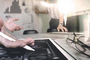 twee collega-swebontwerpers die gegevens en digitale tablet en computerlaptop bespreken met smartphone en ontwerpdiagram op houten bureau als concept foto