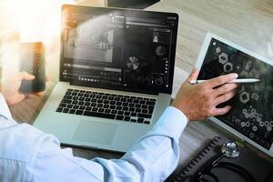 arts die werkt met digitale tablet en laptopcomputer met smartphone in medische werkruimte en videoconferentie als concept foto