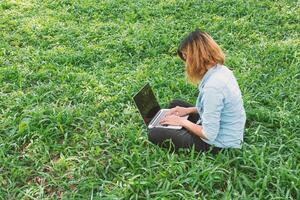 jonge student ontspannen in het park. werk met laptop in groen gras. foto