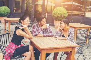 groep jonge hipsters die in een café zitten, jonge vrolijke vrienden die plezier hebben terwijl ze samen tijd nemen, vakantievrijheid genieten. foto