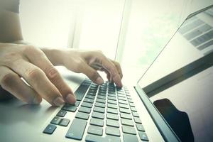 sluit omhoog van bedrijfsmensenhand die aan het lege schermlaptop computer aan houten bureau als concept werken foto