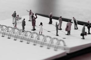 close-up van miniatuurmensen met sociaal netwerkdiagram op open notitieboekje op houten bureau als concept voor sociale media foto