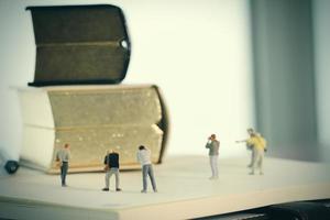 creatief ideeconcept - miniatuurfotograaf met uitstekend gouden boek op open document notitieboekje foto