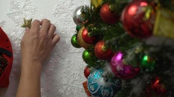 groet seizoen concept.hand instelling van ornamenten op een kerstboom met decoratief licht foto