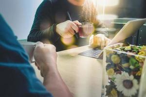 koffiepauze op kantoor met twee designer-collega's die zitten te kletsen over kopjes koffie, bloemenvaas, digitale tablet docking slim toetsenbord op marmeren bureau, filtert effectfilm foto