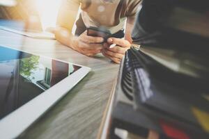 ontwerperhand die met digitale tablet en laptop computer en boekstapel en oogglas op houten bureau als concept werkt foto