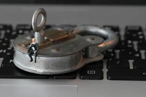 internetbeveiligingsconcept-miniatuur zakenman staat op oude sleutel en hangslot op het toetsenbord van de laptopcomputer foto