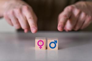 een keuze tussen een man en een vrouw. de wijzers wijzen naar twee houten kubussen met een geslachtspictogram, een mannelijk en een vrouwelijk teken. foto
