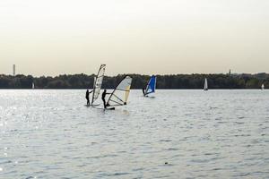 windsurfer. man surft op de achtergrond van wolkenkrabbers. man op een windsurfplank. windsurfen in de stad. watersport. surfen met een zeil. uitrusting voor windsurfen. actieve levensstijl. foto