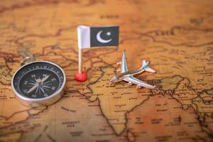 vlag van pakistan, vliegtuig en kompas op de wereldkaart. foto