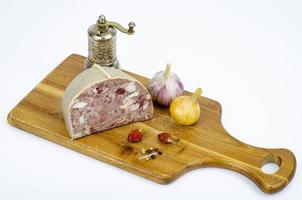 stuk vleesproduct saltison. varkensvlees zelfgemaakte headcheese op een houten bord. heerlijk hapje. studio foto