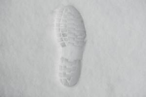 voetafdruk van een schoen in de sneeuw. enkele duidelijk gedefinieerde voetafdruk van een schoen of laars in de sneeuw foto