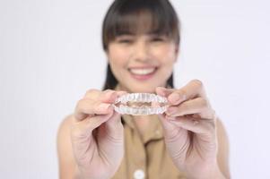 jonge lachende vrouw met invisalign beugels op witte achtergrond studio, tandheelkundige zorg en orthodontische concept. foto