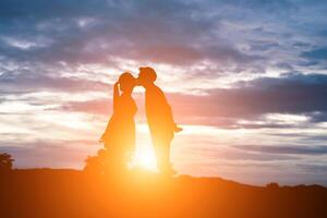 silhouet van zoete paar zoenen over zonsondergang achtergrond. foto