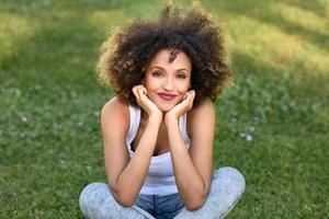 jonge zwarte vrouw met afro kapsel zittend in stadspark foto