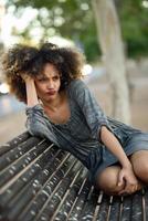 jonge zwarte vrouw met afro kapsel glimlachend in stedelijke achtergrond foto