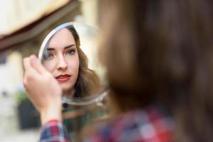 jonge vrouw kijkt naar zichzelf in een kleine spiegel foto