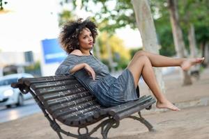 jonge zwarte vrouw met afro kapsel glimlachend in stedelijke achtergrond foto