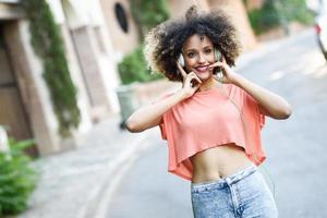 jonge zwarte vrouw met afro kapsel glimlachend in stadspark foto