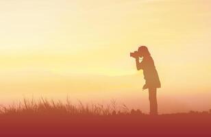 silhouet vrouw fotograaf bij zonsondergang foto