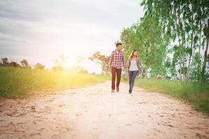 jonge hipster paar wandelen op landelijke weg genieten van met de natuur, liefde paar, vakantie reizen, tijd samen doorbrengen. foto