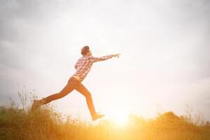 hipster man springt hoog op, vrijheid genietend van de natuur rondom. foto