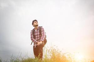 portret van jonge hipster man buiten verhogen handen met rugzak op zijn schouder, avontuurlijk toerisme. foto