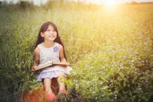 klein schattig Aziatisch meisje leesboek in de natuur. foto