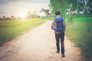 close-up jonge hipster man met rugzak op zijn schouder wandelen door het platteland. foto