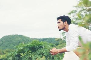 jonge hipster man die rust neemt met de natuur en een frisse bries foto