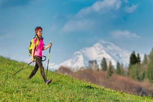 jonge vrouw die in het voorjaar terugkeert van een nordic walking-excursie in de bergen foto