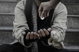 close-up van de armen of daklozen daklozen vragen in het openbaar om geld. de arme bedelaar in de stad zat op de trap met een zilveren mok. foto