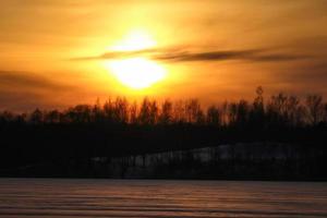 zonsondergang over bos op bevroren meerlandschap foto