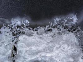 ijsoppervlak met lagen en grote barst op zwart glas macroschot als achtergrond foto