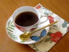 schoonheid koffiekopje staande op houten tafel met donkere smakelijke koffie foto