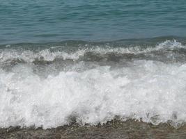 toont het schuim van de zeegolf, natuurvijver, strand foto