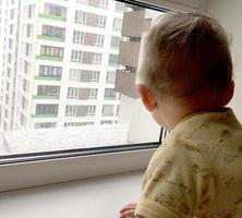 mooie babyjongen met kind gezicht poseren fotograaf in de buurt van raam foto