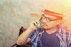 knappe hipster man praten met retro telefoon op de bakstenen achtergrond foto