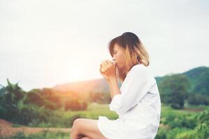 mooie jonge vrouw met een kopje koffie zittend op de bank een frisse bries in de ochtend. foto